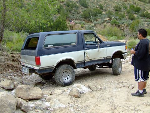 1987 Ford Bronco - This two-tone 1987 Ford Bronco is shown off-road, navigating a rocky trail.