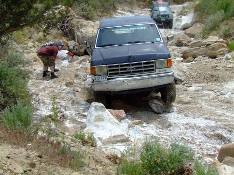 1987 Ford Bronco - Ford Bronco tackling a challenging off-road path with a second vehicle following.