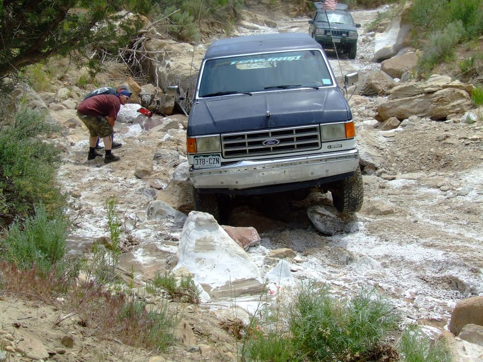 1987 Ford Bronco navigating a rocky trail with another SUV behind it