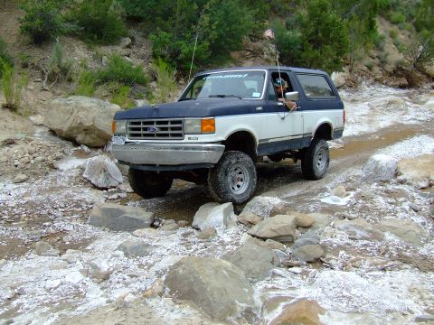 1987 Ford Bronco - This 1987 Ford Bronco is shown off-roading through a rocky, wet terrain.