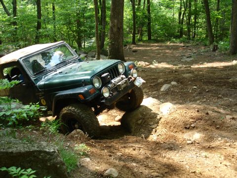 1996 Ford Bronco - A Jeep navigates a challenging off-road course through a wooded area.