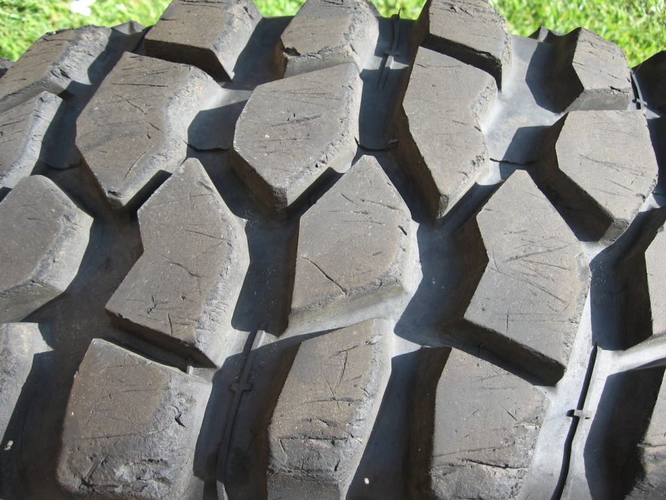 Close-up of chunky mud-terrain tire tread blocks photographed on grass