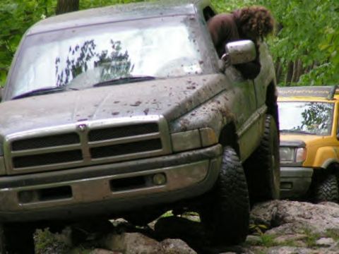 1991 Ford Bronco - Muddy Dodge Ram truck navigating rocky terrain with another vehicle in the background.