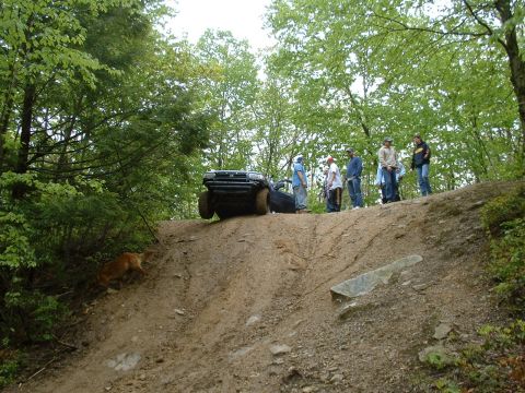 1991 Ford Bronco - A black SUV navigates a challenging dirt incline while onlookers observe the off-road action.