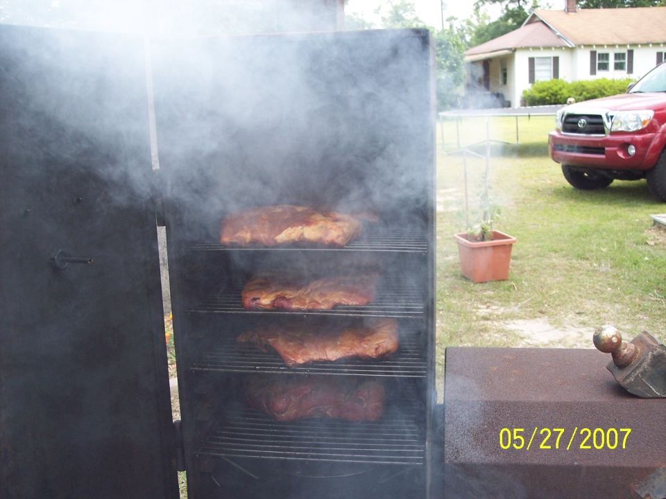 Red Toyota Tacoma parked in yard next to a smoker filled with ribs. Date stamp reads 05/27/2007