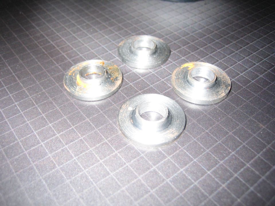 four metal washers with some rust on a grid surface
