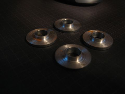 2001 Jeep Wrangler - Four metal washers with rust spots are arranged on a black grid surface.