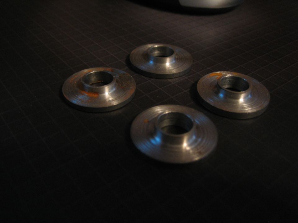 Four metal washers with rust spots on a black grid surface