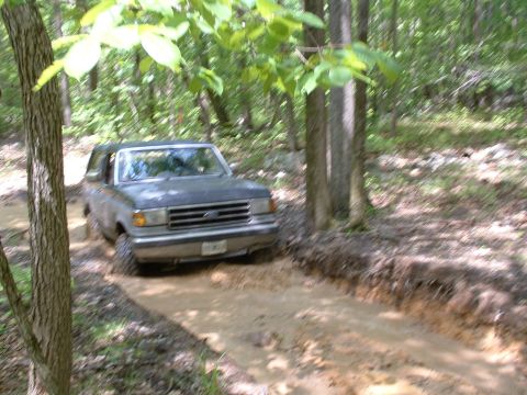 1991 Ford Bronco - Ford Bronco driving through mud on a wooded trail.