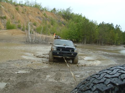 1991 Ford Bronco - A black truck navigates a muddy off-road course, with another vehicle visible in the foreground.