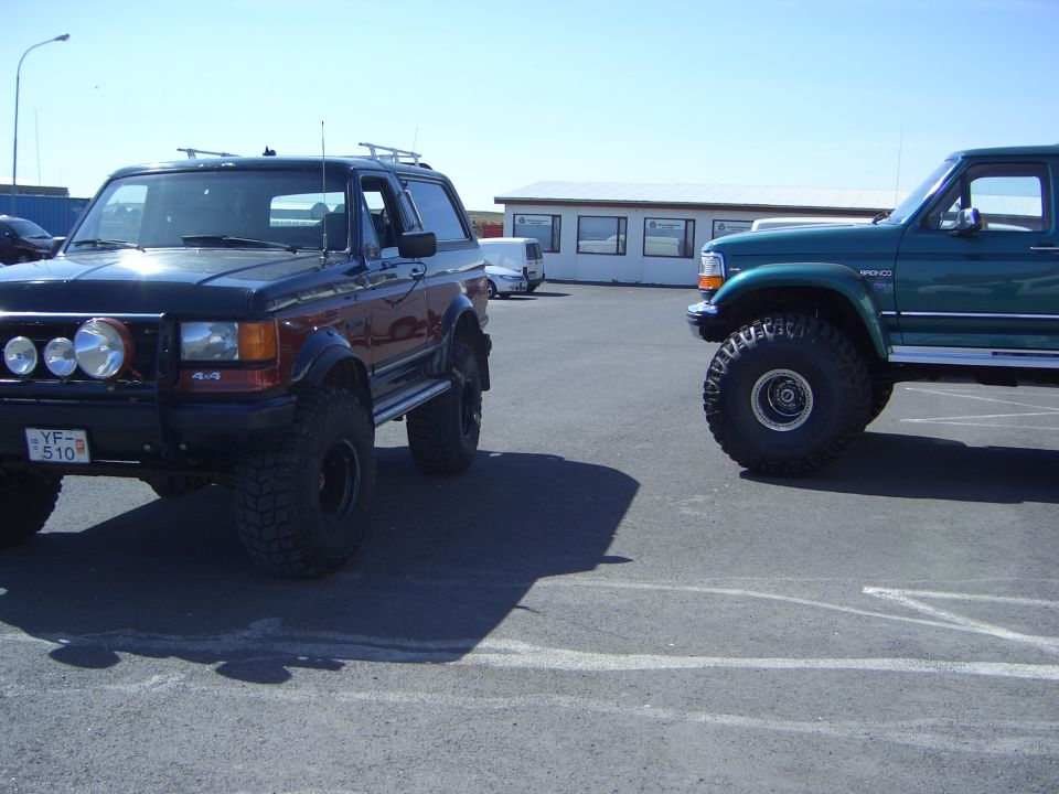 Two lifted Ford Broncos on big tires parked facing each other outdoors