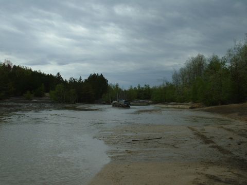 1991 Ford Bronco - A lone SUV navigates a muddy, water-filled terrain under a cloudy sky.
