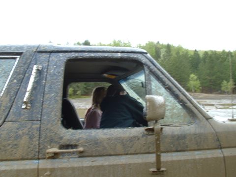 1991 Ford Bronco - A muddy 1987 Ford Bronco is seen from the side, with two occupants visible through the windows.