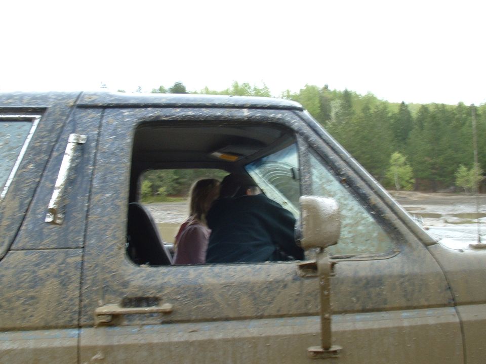 Mud-covered 1987 Ford Bronco side view with two people inside