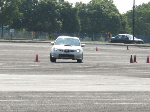 2001 Mercury Grand Marquis - A white Subaru Impreza WRX STI is seen from the front as it maneuvers through an autocross course with orange cones.