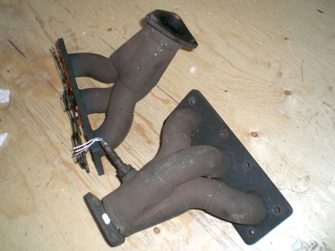 1995 Ford Probe - Exhaust manifolds with an oxygen sensor are shown on a wooden surface.