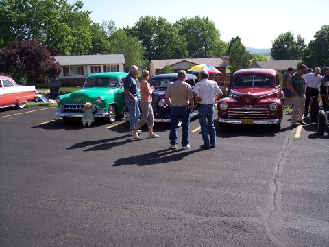1972 Ford Ranchero - A group of people admire a red coupe from the 1940s, possibly a 1946 model, at an outdoor car show.