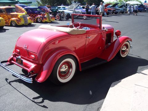 1972 Ford Ranchero - A bright red convertible hot rod is parked at an outdoor car show with other custom vehicles.