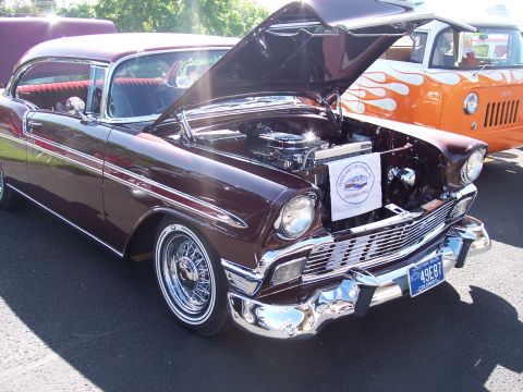 1972 Ford Ranchero - A maroon 1956 Chevrolet Bel Air is displayed with its hood open, revealing the engine and a sign for the "Classic Chevy Club of Colorado."…