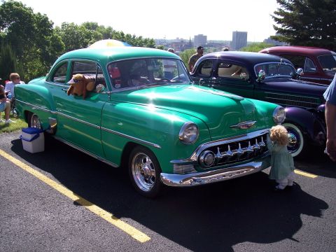 1972 Ford Ranchero - A classic green Chevrolet sedan is displayed at an outdoor event, with other vintage vehicles in the background.