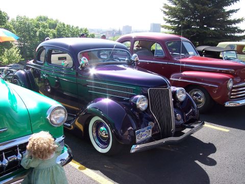 1972 Ford Ranchero - A vintage purple and green coupe is parked alongside other classic cars at an outdoor event.