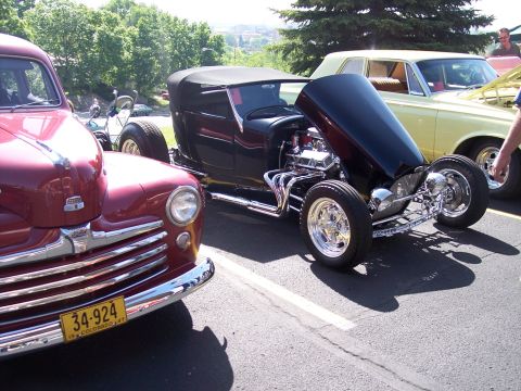 1972 Ford Ranchero - A red 1947 vehicle is parked next to a black hot rod with its hood open, revealing the engine.