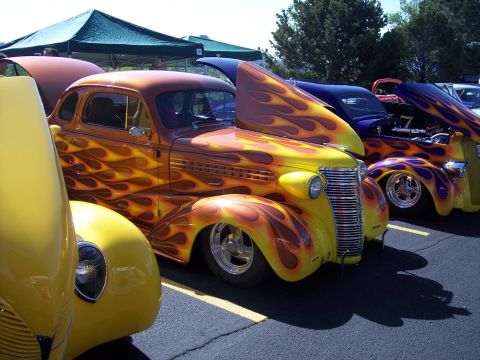 1972 Ford Ranchero - A row of custom hot rods with elaborate flame paint jobs are parked side-by-side under a tent.