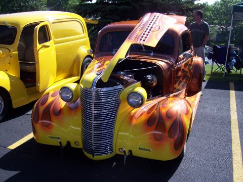 1972 Ford Ranchero - Custom hot rod with flame paint and hood open, parked next to a yellow panel van at an outdoor event.