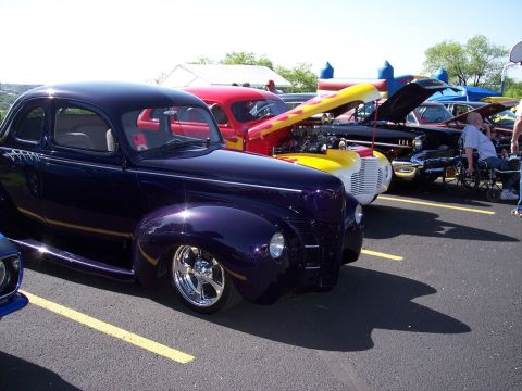 1972 Ford Ranchero - A dark blue pickup truck is parked next to another vehicle, with colorful items loaded in its bed.