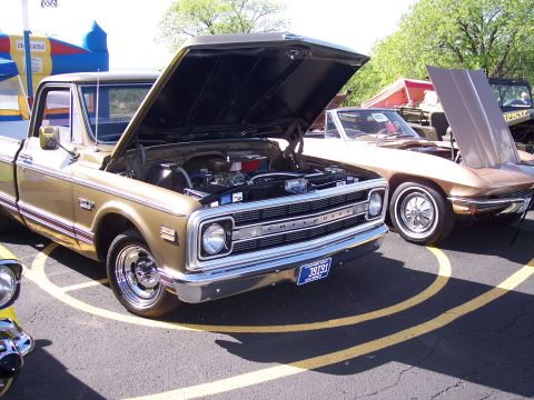 1972 Ford Ranchero - A gold 1970 Chevrolet C10 pickup truck is parked with its hood open, alongside another vehicle.