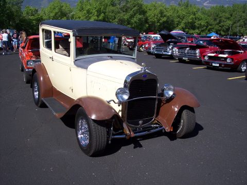 1972 Ford Ranchero - A two-tone 1930s Ford Model A sedan hot rod is parked at an outdoor car show with other vehicles in the background.