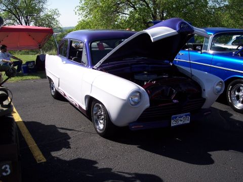 1972 Ford Ranchero - Two custom cars parked side-by-side at an outdoor event, one with its hood up.