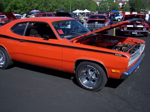 1972 Ford Ranchero - This orange Plymouth Duster, identified by its body style and badging, is displayed with its hood open at a car show.