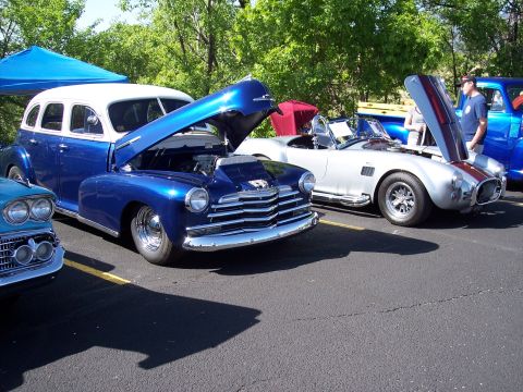 1972 Ford Ranchero - A blue and white sedan is parked with its hood open at an outdoor car show.
