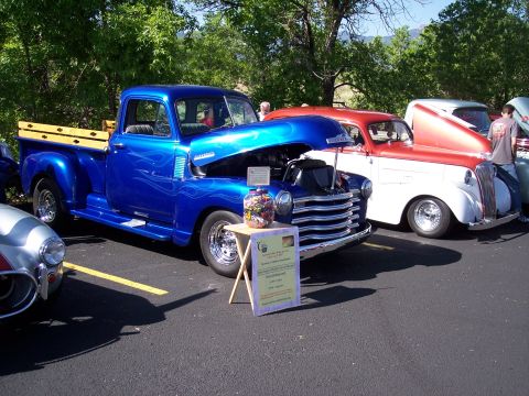 1972 Ford Ranchero - A blue 1950s Chevrolet pickup truck is displayed with its hood open, alongside other classic vehicles.