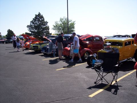 1972 Ford Ranchero - Several custom hot rod vehicles are displayed at an outdoor event, with people milling around.