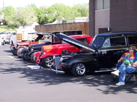 1972 Ford Ranchero - Several vintage automobiles are lined up at an outdoor event, with one black car prominently displayed with its hood raised.
