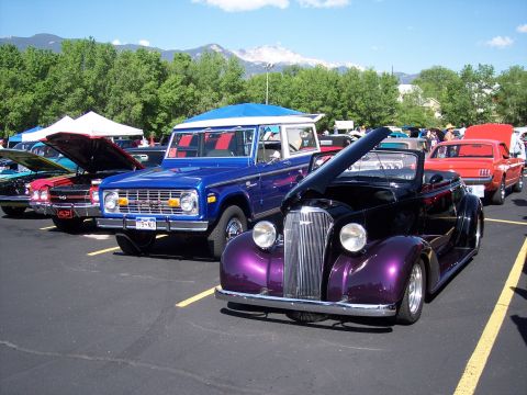1972 Ford Ranchero - A line of classic cars, including a purple convertible and a blue Ford Bronco, are displayed at an outdoor event.