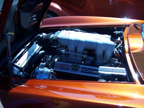1972 Ford Ranchero - The engine bay of an orange car reveals a Chevrolet 502 engine with chrome detailing.