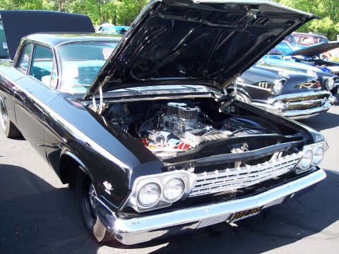 1972 Ford Ranchero - A black 1962 sedan is displayed with its hood open, revealing a V8 engine, while other classic cars are parked nearby.