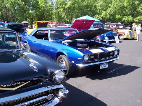 1972 Ford Ranchero - A blue 1968 Chevrolet Camaro SS is displayed with its hood open at a car show, parked alongside a black Chevrolet.