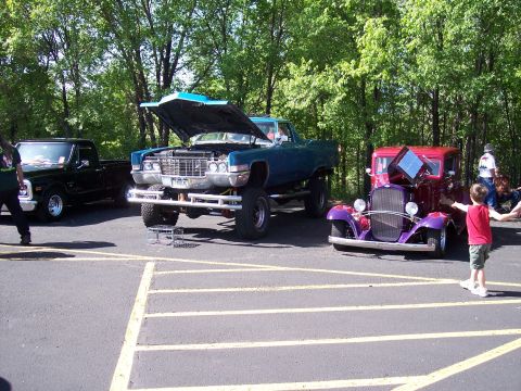 1972 Ford Ranchero - A lifted blue 1971 Cadillac pickup truck is displayed with its hood open next to other vehicles.