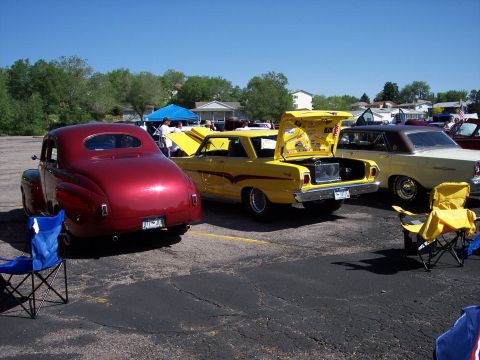 1972 Ford Ranchero - Three classic vehicles are parked in a lot, with the yellow sedan's trunk open, revealing a storage box.
