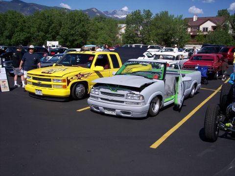 1972 Ford Ranchero - Two modified pickup trucks are displayed at an outdoor event with mountains in the background.