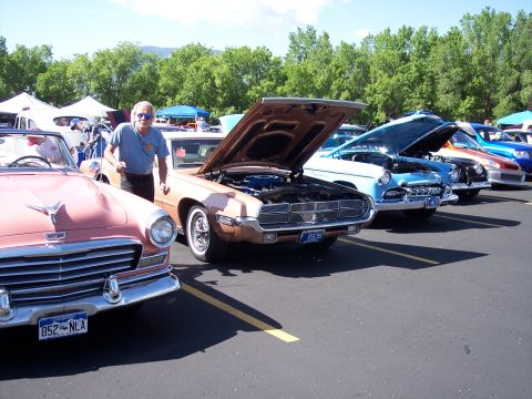 1972 Ford Ranchero - A row of classic cars are displayed at an outdoor event, with one man standing by a copper Ford Thunderbird.