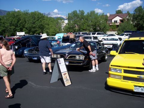 1972 Ford Ranchero - A black 1977 Pontiac Firebird Trans Am is displayed at a car show, with a man cleaning its hood.