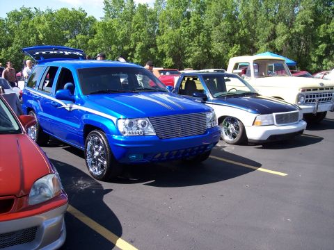 1972 Ford Ranchero - Several vehicles are parked in a lot, including a bright blue SUV with its trunk open.