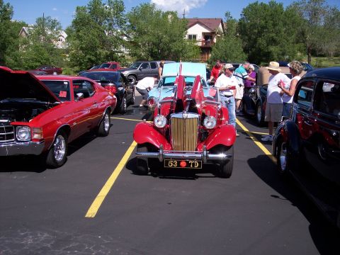 1972 Ford Ranchero - A red classic car with its hood open is displayed at an outdoor event, alongside other vehicles.