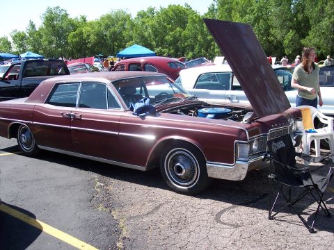 1972 Ford Ranchero - A maroon sedan is parked with its hood open, revealing the engine compartment. Other vehicles and tents are visible in the background.