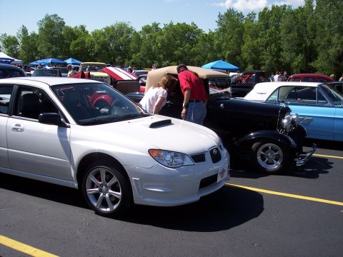 1972 Ford Ranchero - A white Subaru Impreza WRX is parked in a lot with other vehicles and people around.